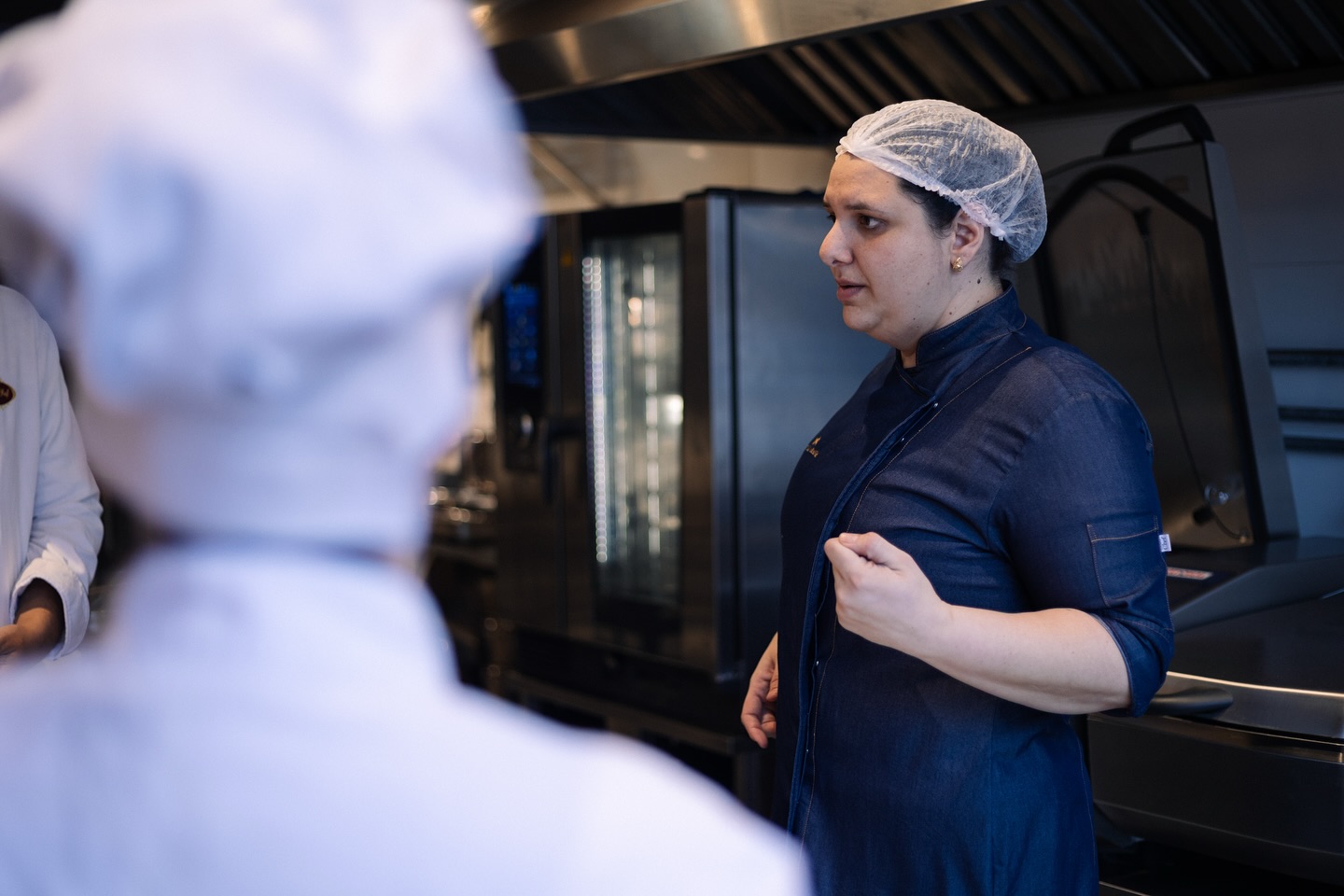 Nattalia em uma cozinha profissional, durante alinhamento com a equipe.